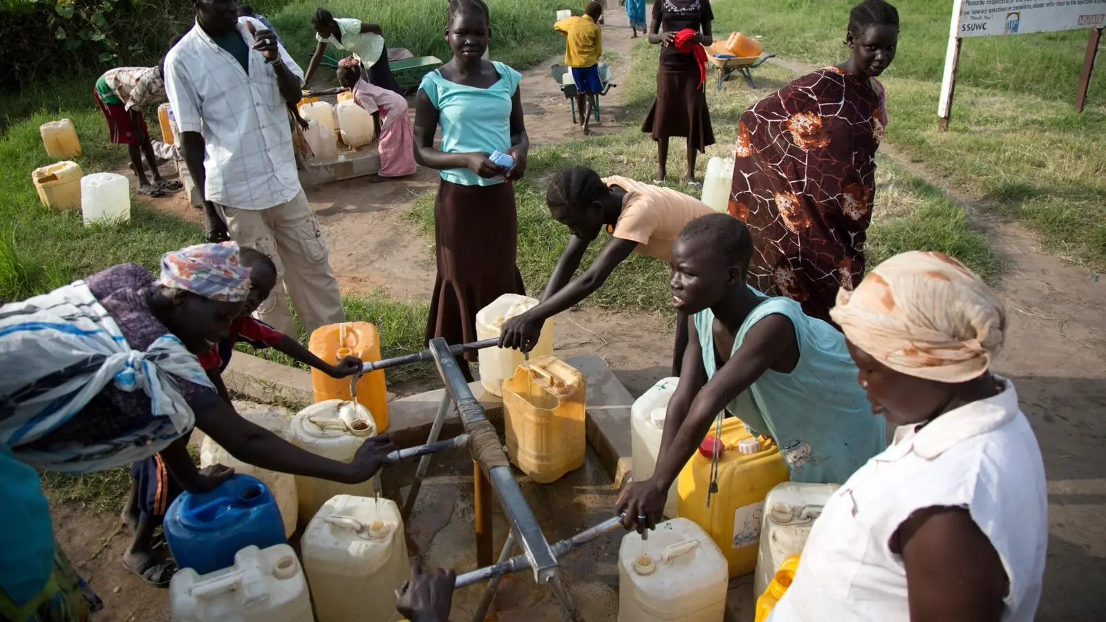 People filling water containers at a water point in a displacement camp
